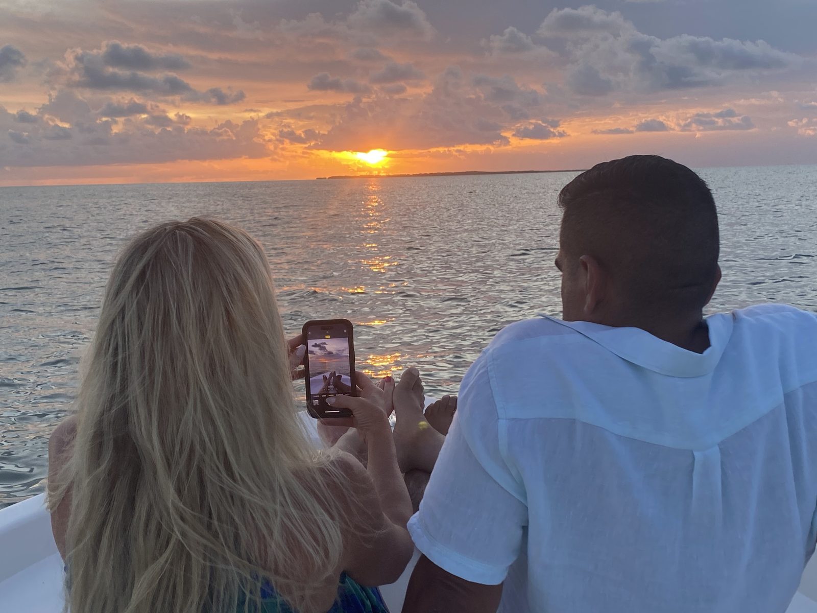 Couple watching a vivid orange sunset over the Florida Keys from the boat