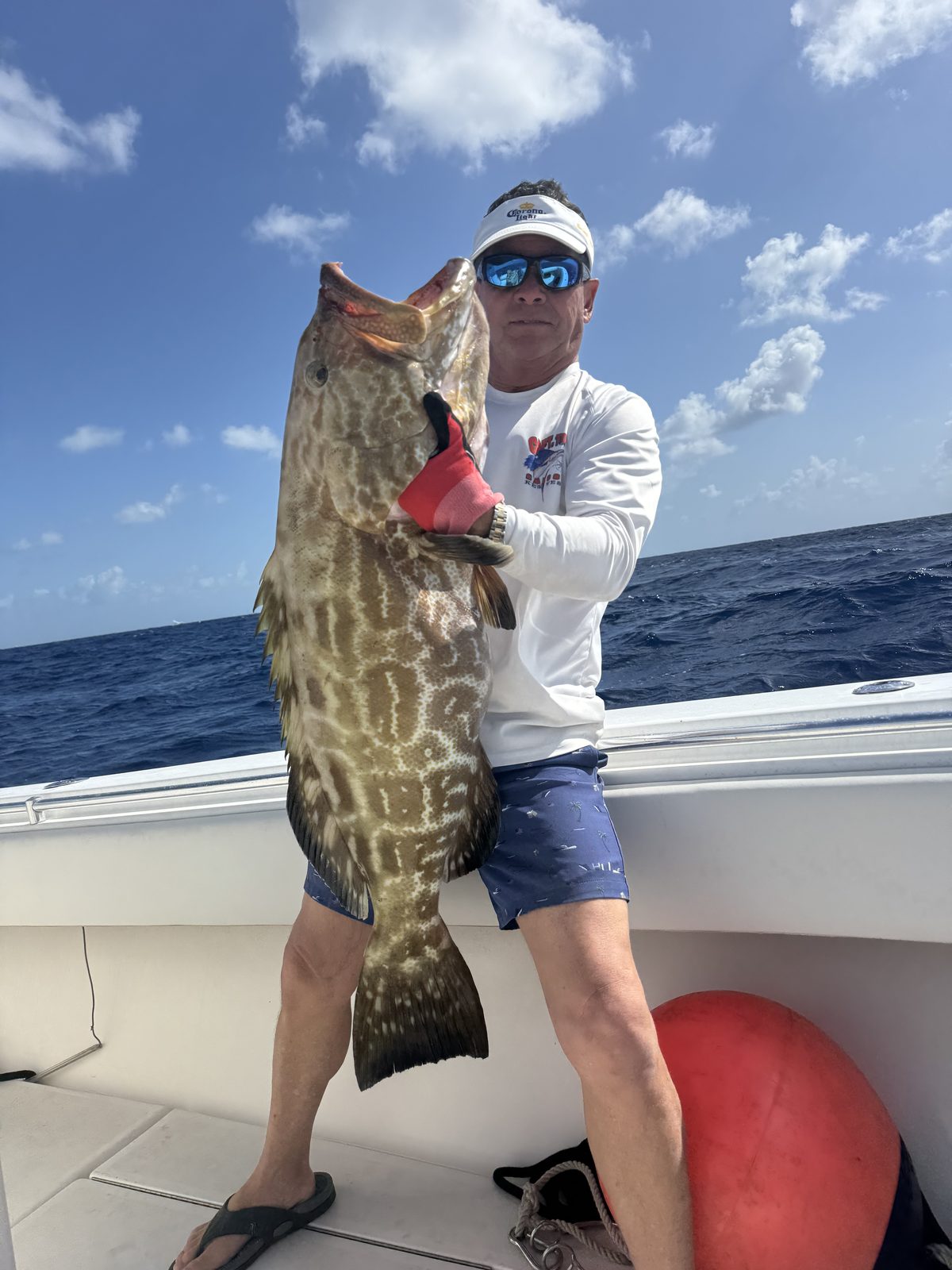 Captain Rene aboard his boat holding a large grouper caught off Islamorada