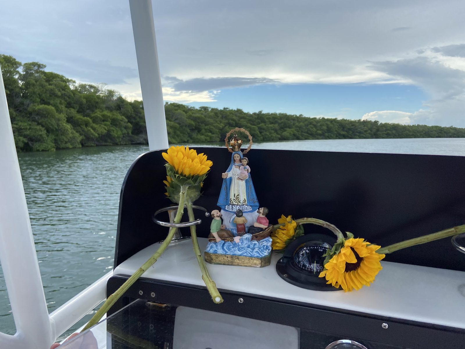 Memorial flowers and the statue set at the boat's helm over calm Keys water
